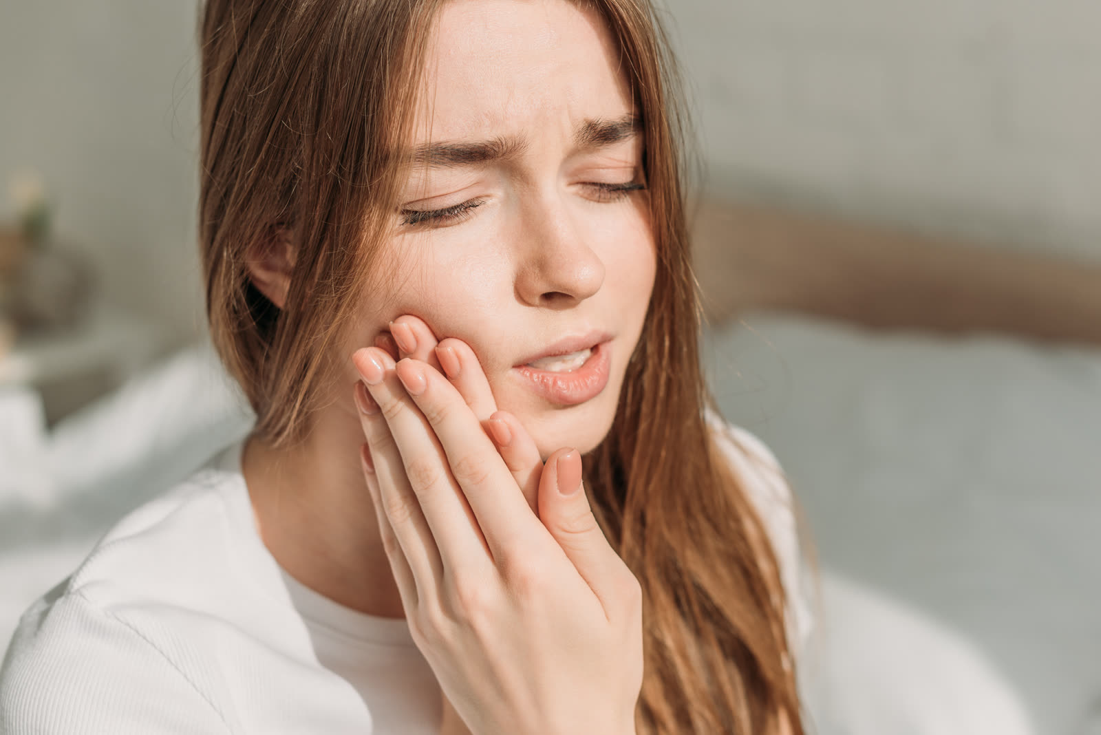 A woman holding her jaw in discomfort